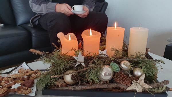 Adventsgesteck mit drei brennenden Kerzen